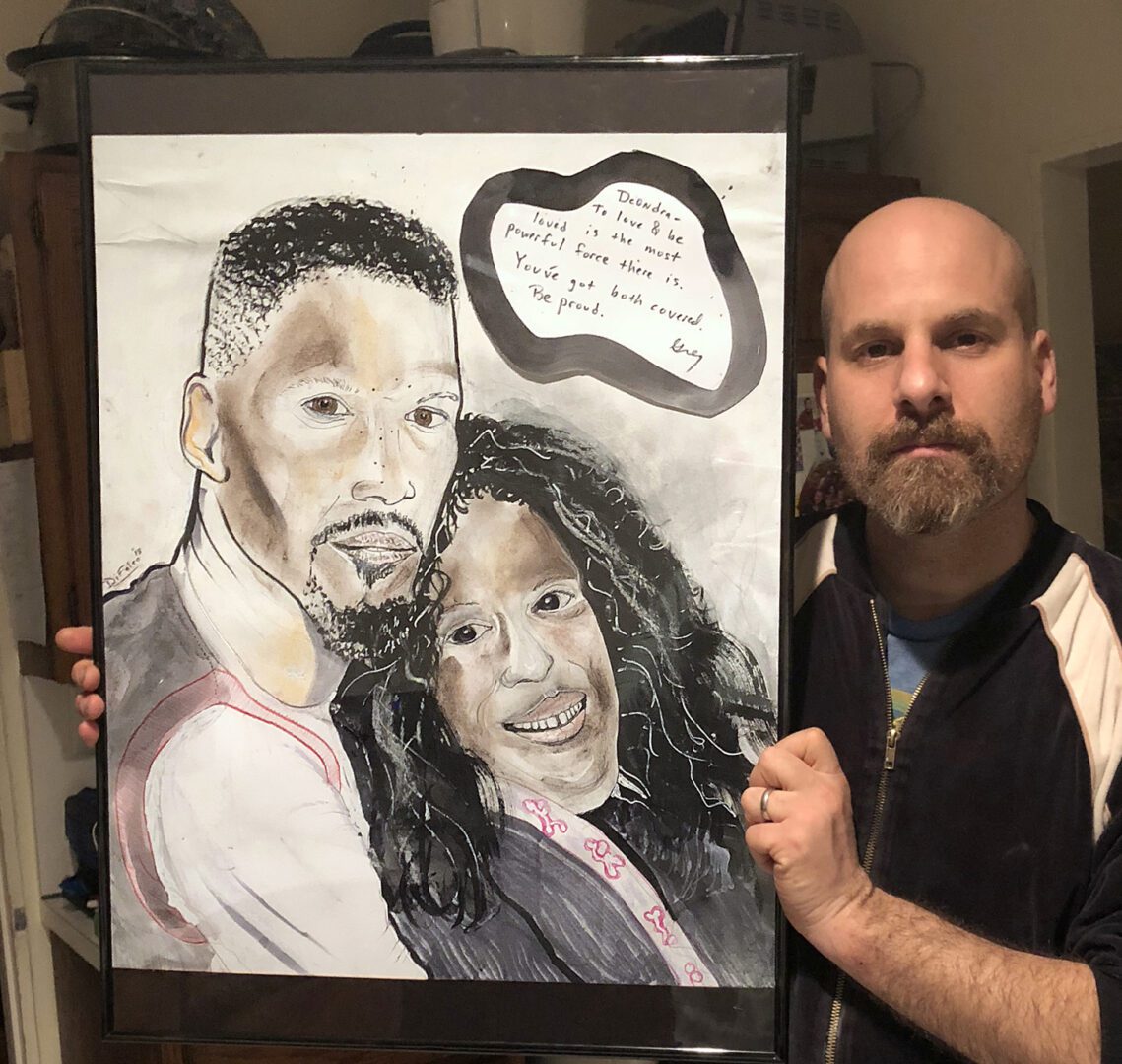 A man holding up a painting of two people.