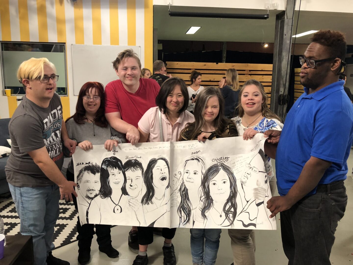 A group of people holding up two large drawings.