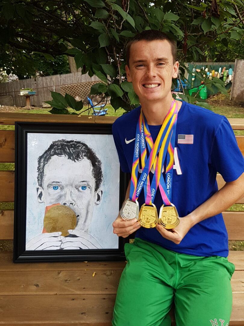 A man holding medals in front of a painting.
